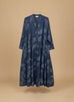A woman wearing a navy blue abaya with a subtle leaf print and a button-front closure. The abaya has a flowing silhouette.