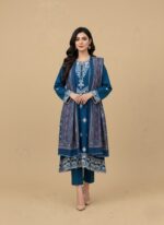 Model in a teal embroidered lawn dress, three-piece summer collection with white embroidery on shirt, patterned dupatta, and trousers.