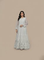 White embroidered net maxi dress with intricate design and a flowing silhouette, next to folded plain white fabric.