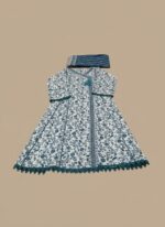 A woman wearing a white and teal floral printed khaddar Angrakha style suit with a long-sleeved, flared kurta, matching teal trousers, and a coordinating printed khaddar dupatta draped over her head.