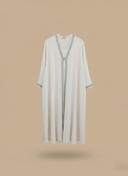 Woman abaya in sand beige, open-front kimono sweater cut, side pockets and belt shown on model standing against neutral wall