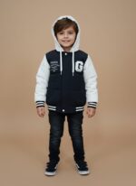 Front view of a black and white Kids Varsity Puffer Jacket with a white hood and sleeves, a black body, and white "GABS" text and a large "G" graphic, worn by a child against a plain background.