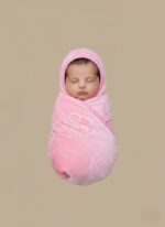 Pink baby blanket with hood, ultra-soft coral fleece with embossed rose pattern and pink trim, folded neatly on a neutral background, for baby girls.