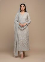 Flat lay of an ivory/light beige Embroidered Chiffon Dress material. Includes a heavily embroidered and embellished chiffon shirt piece, a stone work dupatta, dyed printed rawsilk trouser, and raw silk inner fabric pieces. Ideal for formal Pakistani/Indian attire.