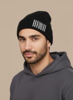 Image of a man wearing a black ribbed beanie with white vertical stripes and a diagonal patterned section on the cuff.