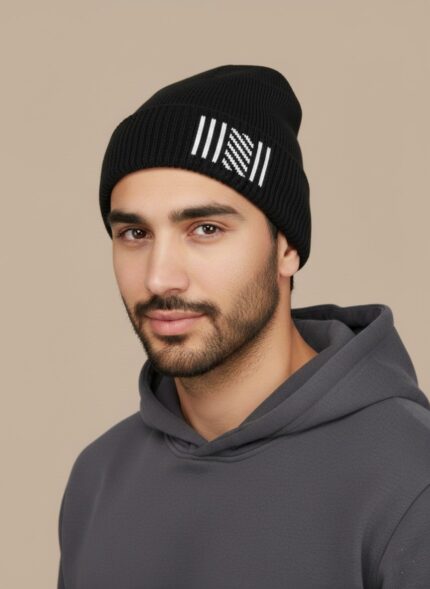 Image of a man wearing a black ribbed beanie with white vertical stripes and a diagonal patterned section on the cuff.