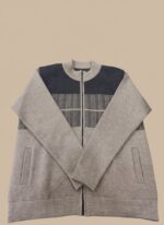 A man wearing a men's color block full zip sweater in light grey and dark charcoal grey with a full zipper, dark blue jeans, and white sneakers, standing against a plain background.