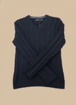 Men's navy cable knit V-neck sweater with an intricate textured pattern, worn by a model and layered over a light blue shirt.
