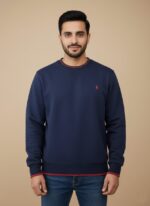 Men's navy crew neck sweater with red striped trim on the collar, cuffs, and hem, worn by a model.