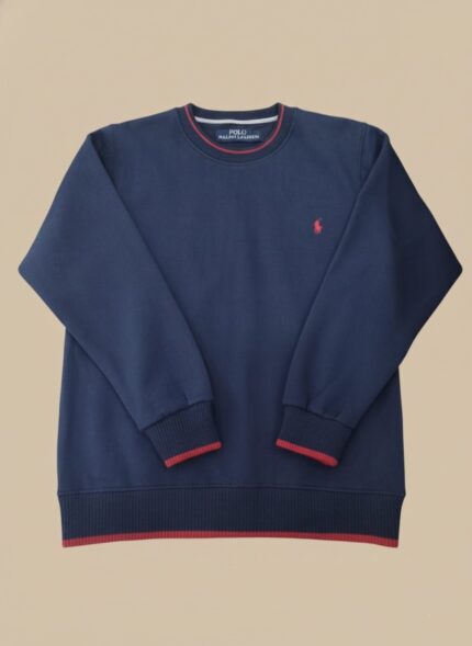 Men's navy crew neck sweater with red striped trim on the collar, cuffs, and hem, worn by a model.
