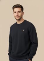 Men's navy textured crew neck sweater with a delicate pattern and a yellow embroidered logo, worn by a model.