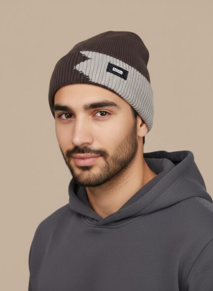 Image of a man wearing a brown and light grey/beige two-tone ribbed beanie with a black "DESIGN" tag on the fold.