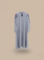 Neutral woman abaya in matte crepe, open-front kimono sweater silhouette, side pockets and belt shown on model against light grey wall