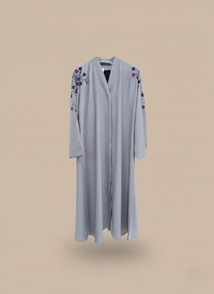 Neutral woman abaya in matte crepe, open-front kimono sweater silhouette, side pockets and belt shown on model against light grey wall