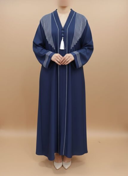 A woman wearing a navy blue abaya with white embroidered lines on the shoulders and down the front, featuring a white tassel at the V-neck.
