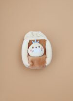 White baby pillow with a colorful car, palm tree, and sun illustration, set against a light brown background.