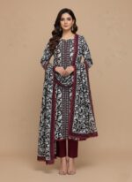A woman wearing a black and white abstract floral printed khaddar suit with a long-sleeved shirt, matching maroon trousers, and a coordinating printed khaddar dupatta. The suit features maroon lace trim.