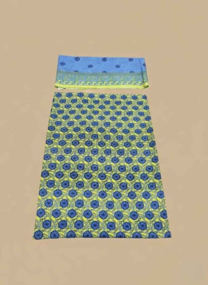 A 3-piece set of unstitched Lawn Suit fabric. The shirt piece is yellow with blue floral block prints. The dupatta piece is light blue with a patterned border. The third piece is folded underneath.