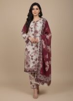 Full-length image of a woman wearing a white and maroon Women's Printed Suit with palm tree and floral prints on the long-sleeve tunic and trousers, and a maroon printed dupatta.