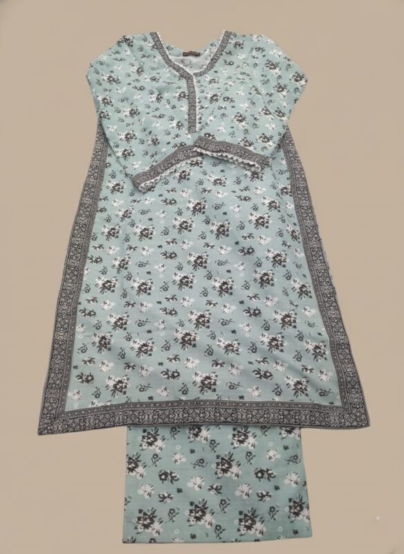 Half-length image of a woman wearing a light blue Women's Floral Suit with an all-over black and white floral printed long-sleeve tunic featuring an embroidered V-neckline, cuffs, and hem, and matching patterned trousers.