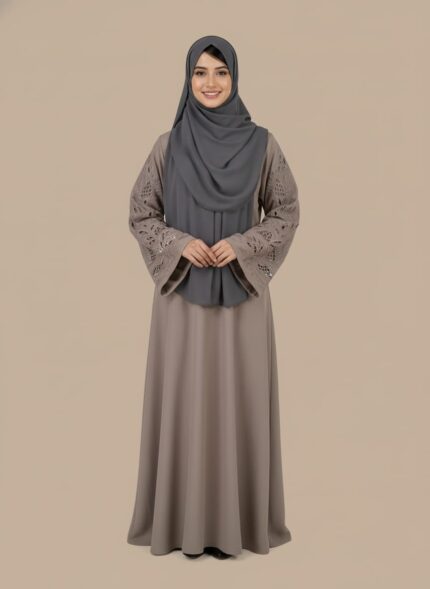Chic taupe abaya dress with intricate cut-out lace sleeves and a grey hijab, modeled by a smiling woman. A sophisticated modest fashion sweater.
