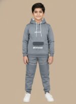 Happy boy in a full grey tracksuit set, consisting of a hooded top with bear graphic and "HELLO BUDDY" print, matching joggers with white stripes, and white sneakers.