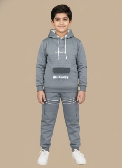 Happy boy in a full grey tracksuit set, consisting of a hooded top with bear graphic and "HELLO BUDDY" print, matching joggers with white stripes, and white sneakers.
