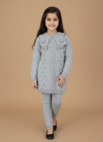 Full-length image of a smiling young girl wearing a grey knitted Girls Grey Sweater Set, including a long-sleeve sweater with a large embellished collar and matching leggings, standing against a beige background.