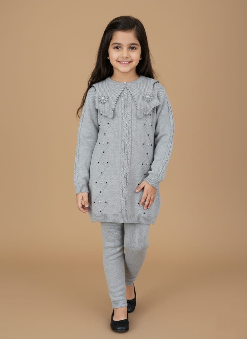 Girls Grey Knitted Sweater & Leggings Set - Embellished Winter Outfit Full-length image of a smiling young girl wearing a grey knitted Girls Grey Sweater Set, including a long-sleeve sweater with a large embellished collar and matching leggings, standing against a beige background.