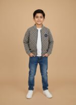Happy boy in a grey patterned bomber jacket with a monogram print and badge, white t-shirt, blue jeans, and white sneakers,