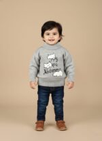 Happy toddler boy or girl in a grey mock neck sweater with a "Happy Pupu Andamma" graphic and white clouds, blue jeans, and brown shoes.