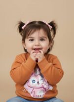 A comfortable, earth-tone kids character sweater with long sleeves, showcasing a large, colorful graphic print of a pink winking bunny character inside a heart with stars.