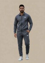 Main Image: Full view of Gelani's gray Tracksuit for Men with white logo branding. Jacket Detail: Close-up of the gray dry-fit jacket zipper and stand-up collar. Logo Detail: The North Face white logo on the chest of the gray men's tracksuit. Trousers View: Matching gray dry-fit trousers for men with elasticated waist and logo. Fabric Shot: High-quality gray stitched dry-fit material texture for winter athletic wear. Tracksuit for Men
