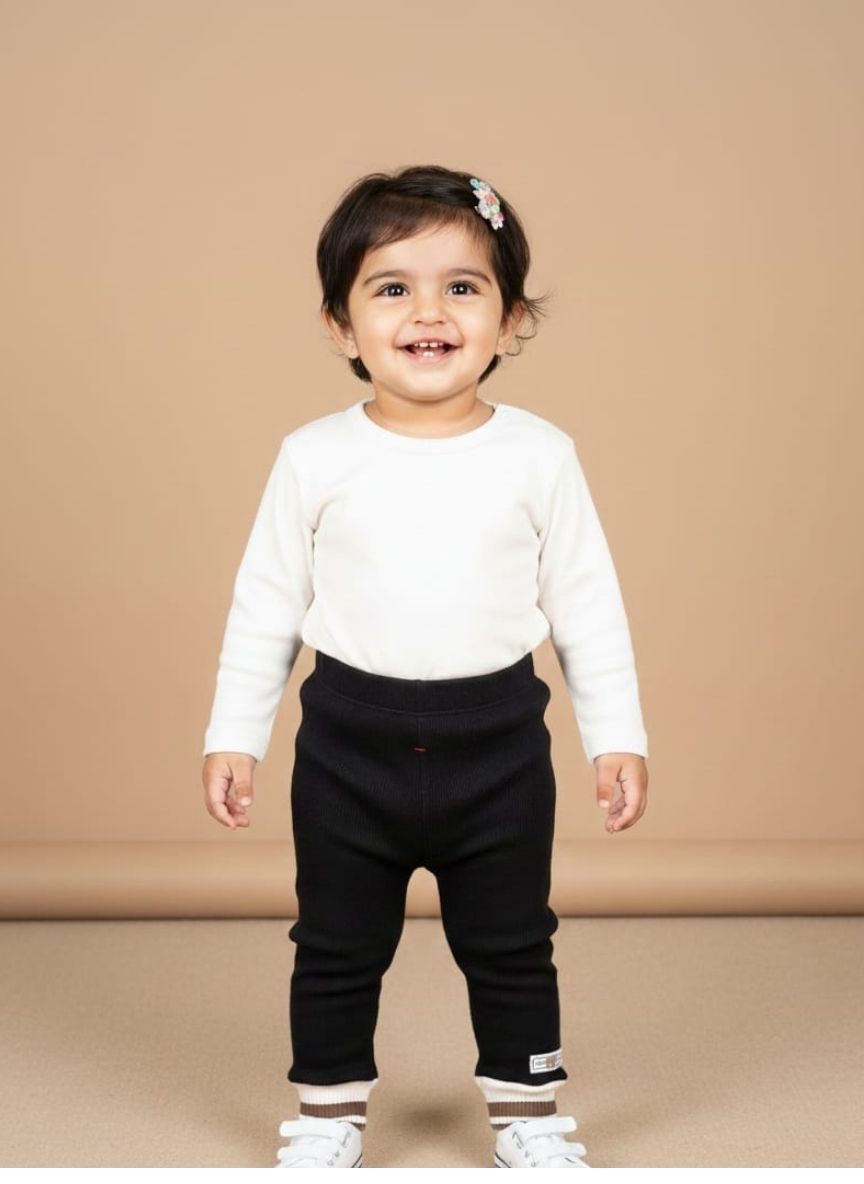 Folded pair of plain black stretch leggings for kids, featuring a smooth, design and an elastic waistband.
