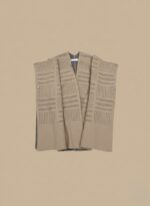 Beige women sweater shawl worn over black dress, sleeveless knit wrap for winter layering.