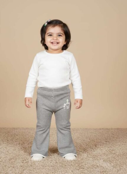 Flat lay view of brown ribbed knit baby pants with a small white animal graphic on the lower right leg and cuffed ankles.