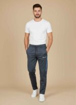 Front view of dark gray champion track pant for men on a neutral background. Close-up of the stitched jersey fabric and side-stripe detail on men's joggers. Men's winter athletic trousers in navy blue with elasticated waistband. Detailed shot of the zipper pocket and brand logo on jersey track pants. Black champion track pant for men showing the tapered leg and cuffed ankle. champion track pant for men